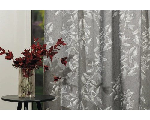 Cortină decorativă cu model floral lângă o măsuță laterală cu o vază de flori