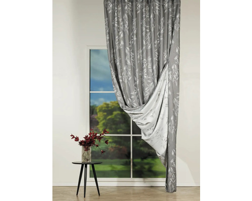 Cortină decorativă cu model floral în fața unei ferestre.
