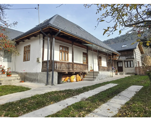 Vedere exterioară a unei case cu țigle gri și o potecă adiacentă.