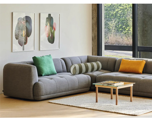 Cameră de zi cu canapea de colț gri, perne, măsuță de cafea și tablouri