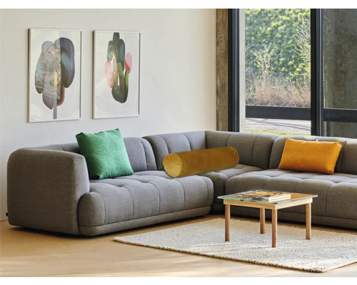 Canapea de colț gri cu perne și măsuță de cafea în camera de zi.