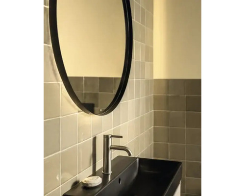 Baie modernă cu oglindă ovală, lavoar dreptunghiular şi perete cu faianţă