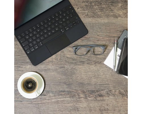 Scenă cu o tabletă, o ceașcă de cafea, ochelari, un blocnotes, un stilou și un telefon mobil pe o masă de lemn