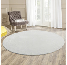 Covor rotund în sufragerie cu fotoliu și lumină naturală.