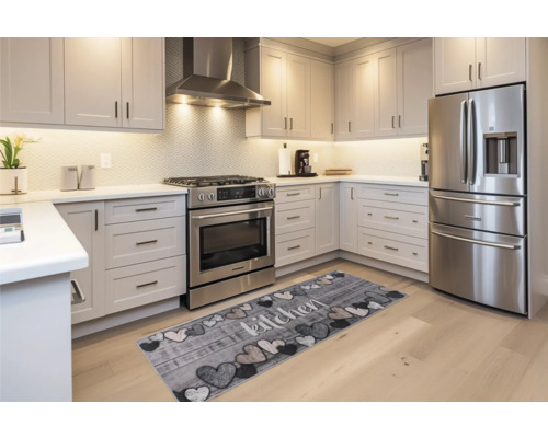 Bucătărie luminoasă cu electrocasnice moderne și un covor cu motiv inimă și inscripția 'bucătărie'.