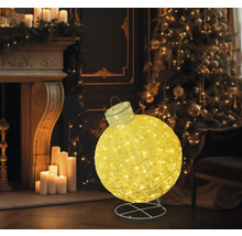 Glob decorativ, luminos de Crăciun, în fața unui șemineu și a unui brad de Crăciun