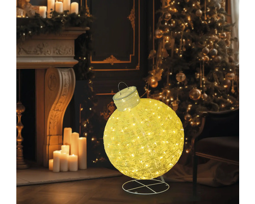 Glob decorativ, luminos de Crăciun, în fața unui șemineu și a unui brad de Crăciun