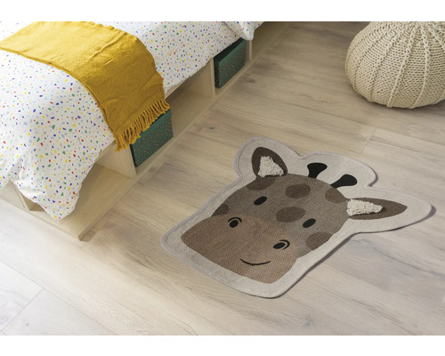 Scenă de cameră cu pat, pernă de șezut și covor în formă de cap de girafă.