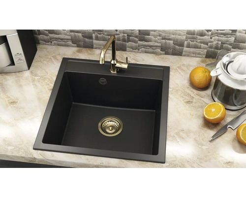 Chiuvetă de bucătărie neagră cu robinet auriu și coș de sită pe un blat.