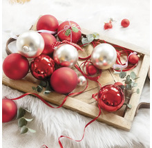 Globuri decorative de Crăciun în roșu și argintiu pe o tavă de lemn.