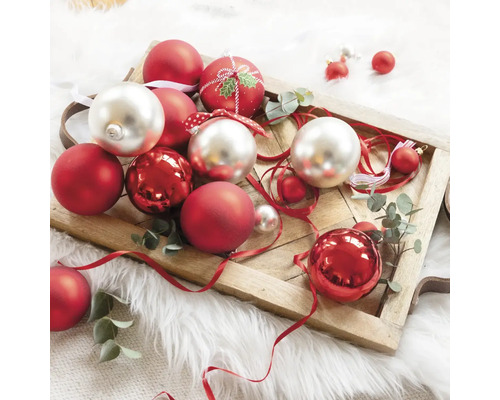 Globuri decorative de Crăciun în roșu și argintiu pe o tavă de lemn.