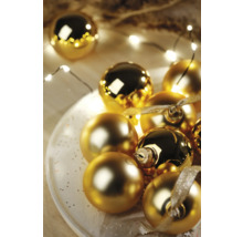 Globuri decorative aurii de Crăciun pe o farfurie cu șir de lumini