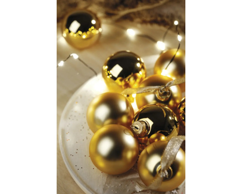 Globuri decorative aurii de Crăciun pe o farfurie cu șir de lumini