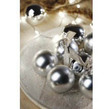 Globuri decorative de pom de Crăciun cu suprafață lucioasă și funde pe o farfurie