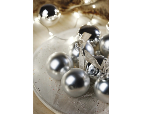 Globuri decorative de pom de Crăciun cu suprafață lucioasă și funde pe o farfurie