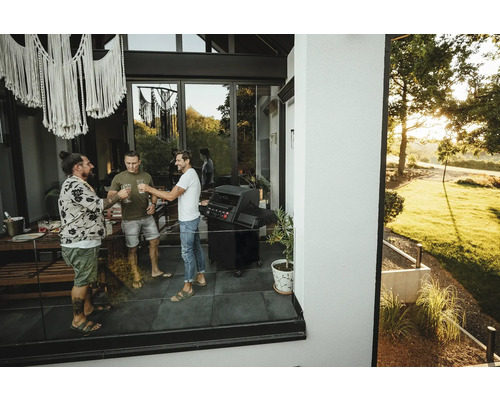 Trei bărbați ciocnesc pe terasă cu un grătar.