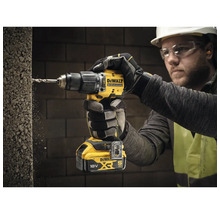 Un bărbat găurește un perete cu o mașină de găurit DeWalt.