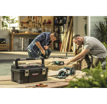 Scenă de atelier cu cutie de scule, ferăstrău de mână și doi meșteri la lucru