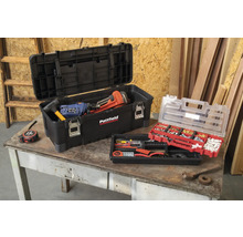 Cutie de scule deschisă cu scule și sortiment de piese mici pe o masă.