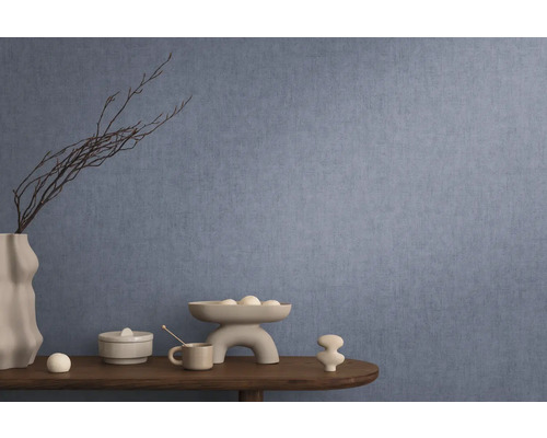 Interior decorativ cu tapet albastru, masă cu decorațiuni precum vază, bol și figurine ceramice