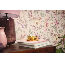 Scenă de interior cu tapet floral, lampă de masă, vaze, cărți și bol.
