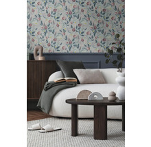 Cameră de zi cu tapet cu model floral, canapea, masă și decorațiuni pentru o ambianță primitoare.
