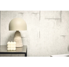 Lampă decorativă de masă cu bază din travertin lângă o lumânare tip bulă pe o masă