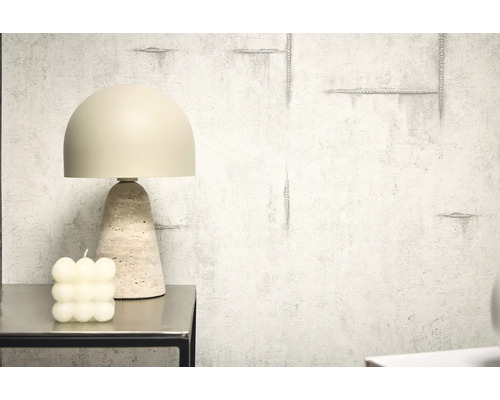 Lampă decorativă de masă cu bază din travertin lângă o lumânare tip bulă pe o masă
