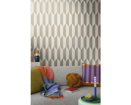 Cameră de zi cu tapet geometric în gri și alb în spatele unei canapele gri
