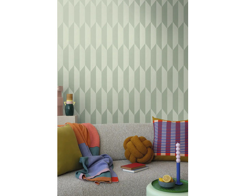 Cameră de zi cu canapea gri, perne, pături și un perete cu tapet geometric