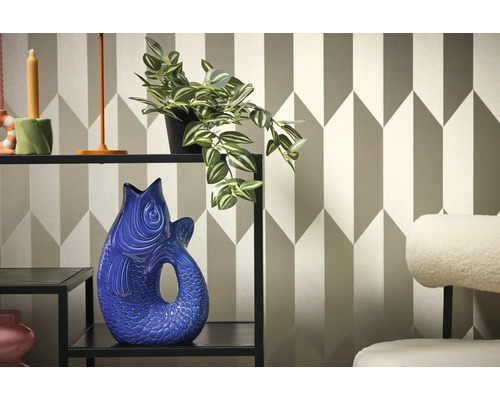 Interior decorativ cu raft, plantă și vază în formă de pește pe un fundal de tapet geometric.