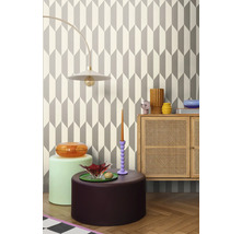 Cameră de zi cu tapet geometric, lampă, comodă și obiecte decorative pentru un interior stilat.
