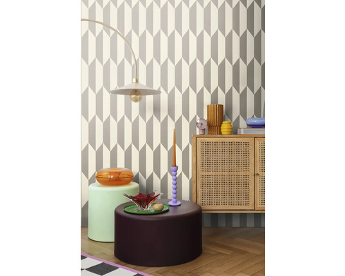 Cameră de zi cu tapet geometric, lampă, comodă și obiecte decorative pentru un interior stilat.