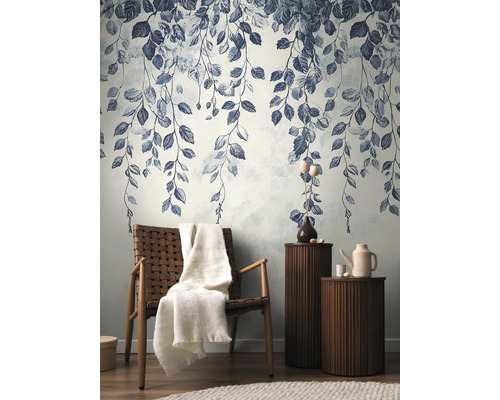 Tapetă decorativă cu model de frunze într-un living elegant, cu fotoliu și măsuțe laterale.