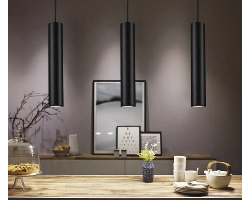 Trei lămpi suspendate negre deasupra unei mese într-o sufragerie.