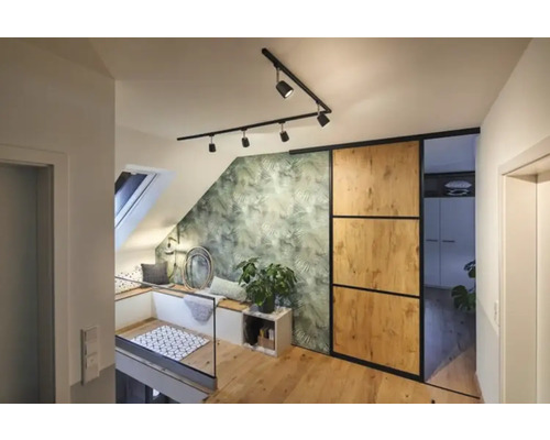 Apartament luminos la mansardă cu fereastră de mansardă, zonă de relaxare, tapet verde cu frunze, ușă glisantă și podea din lemn.