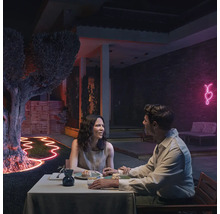 Un cuplu stă la o masă în grădină, iluminată cu un tub luminos flexibil