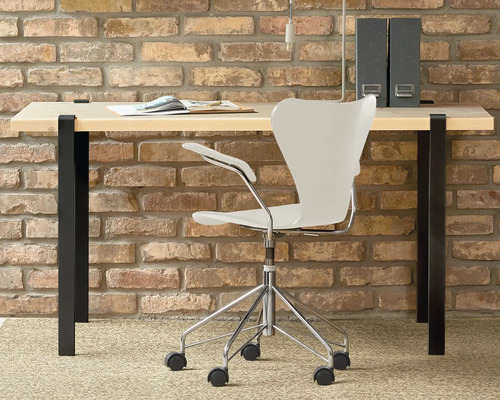 Birou cu masă de scris, scaun de birou și bibliorafturi în fața unui perete de cărămidă