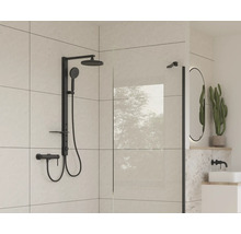 Baie modernă cu armătură de duș neagră și perete de sticlă.