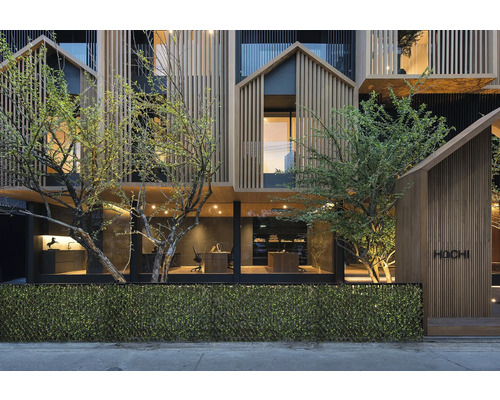 Fațada unei clădiri moderne cu placare din lemn și vegetație