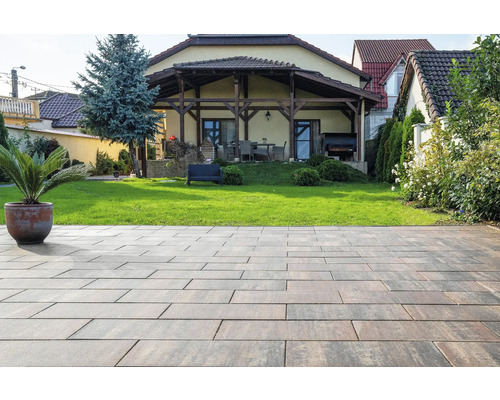 Terasă pavată cu casă și grădină în fundal