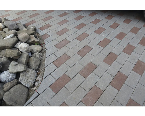 Pavele în două culori și pietre rotunde ca margine de strat de flori