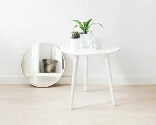 Scenă decorativă cu oglindă rotundă, măsuță laterală, plante de interior și sculptură