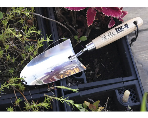 Plantator din oțel inoxidabil cu mâner din lemn într-un strat de flori