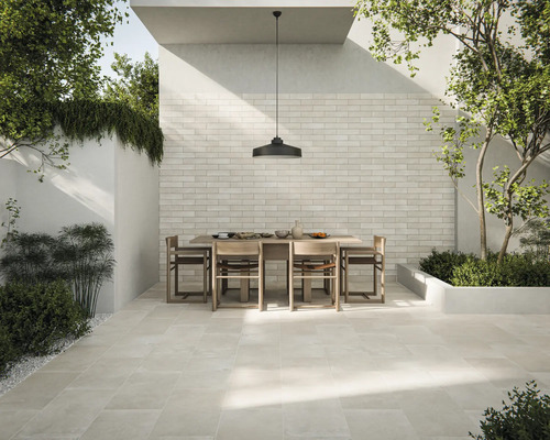 Zonă de terasă luminoasă cu gresie, masă și scaune afară