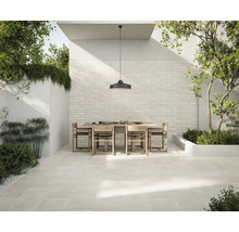 Terasa cu podea de piatră deschisă la culoare, masă de sufragerie cu scaune și perete cu placaj de cărămidă