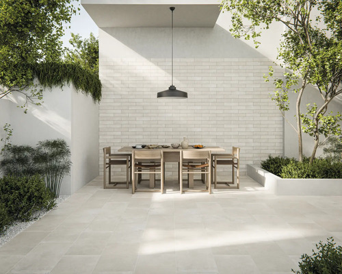 Terasa cu podea de piatră deschisă la culoare, masă de sufragerie cu scaune și perete cu placaj de cărămidă