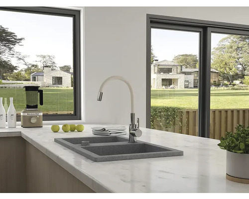 Scenă de bucătărie cu chiuvetă, robinet și aparate de bucătărie pe un blat de marmură în fața unei ferestre