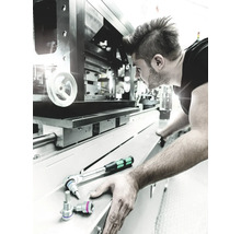 Un bărbat lucrează la o mașină cu o cheie cu clichet și chei tubulare.