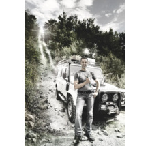 Bărbat cu șurubelniță stând în fața unui vehicul de teren pe un drum pietruit